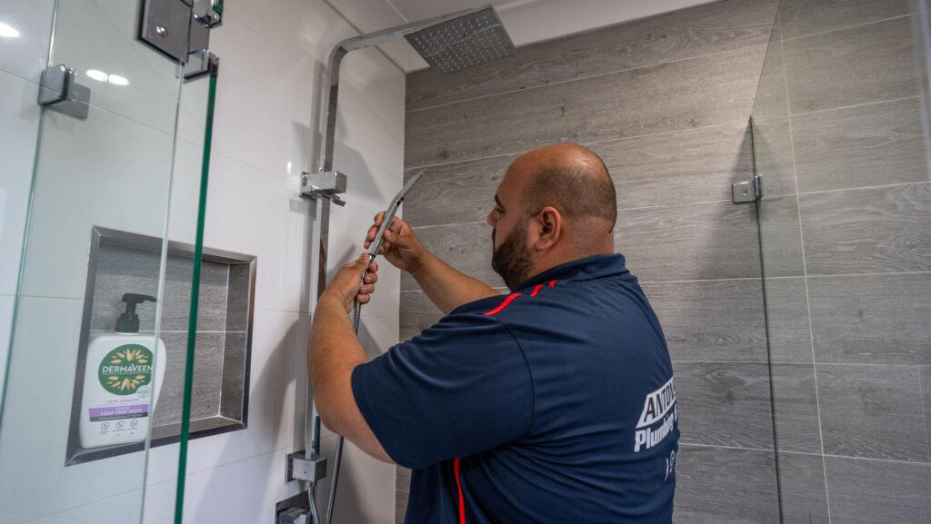 A professional plumber from Anton's Plumbing performs a shower fixture repair, showcasing expertise in Emergency Plumbing & Gas solutions.